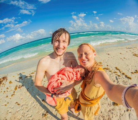 Téléchargez les photos : Les nouveaux parents chérissent une journée à la plage avec leur nouveau-né un moment familial chaleureux au bord de la côte. - en image libre de droit