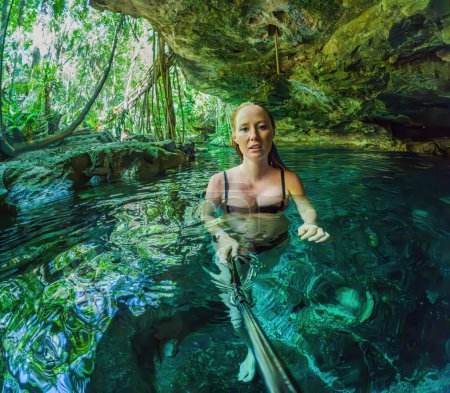 Photo for Woman immersed in the enchanting beauty of a Mexican cenote, surrounded by crystal-clear waters and captivating natural formations. - Royalty Free Image