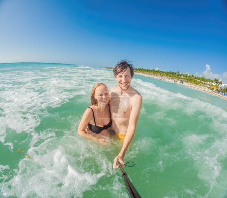 Téléchargez les photos : Au milieu de la mer turquoise tranquille, une femme enceinte et son mari partagent un moment serein, célébrant la beauté de la parentalité imminente dans les douces vagues. - en image libre de droit