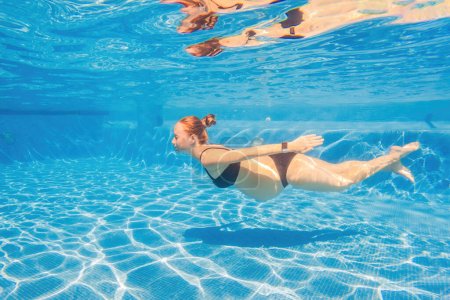Foto de La serenidad embarazada sumergió a una mujer en la piscina, celebrando la belleza del embarazo con elegancia acuática. - Imagen libre de derechos