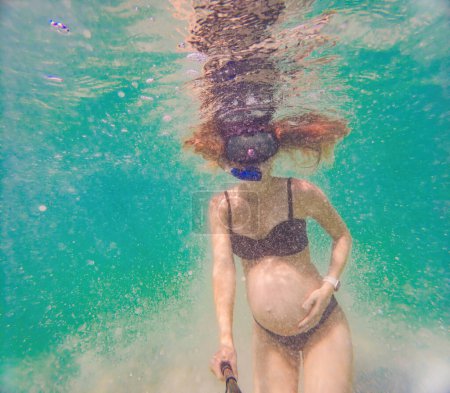 Photo for In an ethereal underwater scene, a pregnant woman gracefully floats, embodying the beauty of maternity beneath the tranquil surface of the sea. - Royalty Free Image