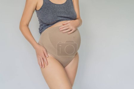 Photo for Pregnant bliss: Mom-to-be embraces her baby bump with a soft fabric bandage, providing gentle support. Maternity made comfortable. - Royalty Free Image