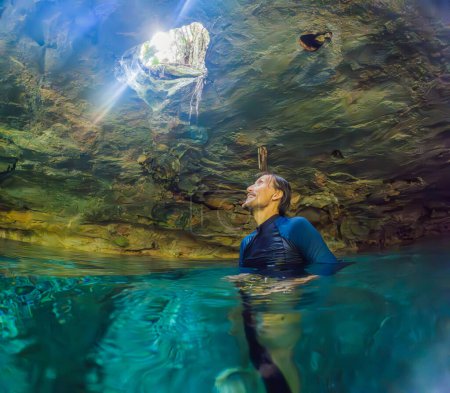 Foto de Hombre inmerso en la encantadora belleza de un cenote mexicano, rodeado de aguas cristalinas y formaciones naturales cautivadoras. - Imagen libre de derechos