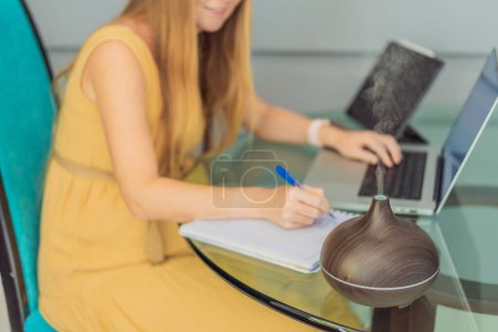 Expectant woman enhances work environment, using an aroma diffuser for a soothing atmosphere during pregnancy.