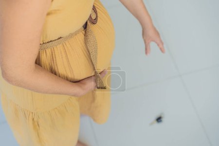 Téléchargez les photos : Face à un défi momentané, une femme enceinte laisse tomber ses clés et peine à les récupérer, soulignant les limitations physiques qui peuvent survenir pendant la grossesse. Patience et soutien deviennent - en image libre de droit