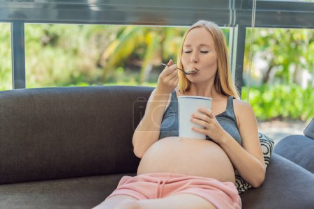 Téléchargez les photos : Joyeux enceinte jeune femme manger de la crème glacée. - en image libre de droit