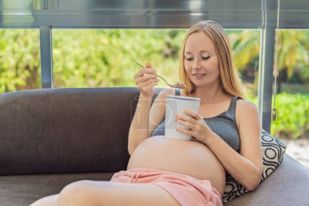 Téléchargez les photos : Joyeux enceinte jeune femme manger de la crème glacée. - en image libre de droit