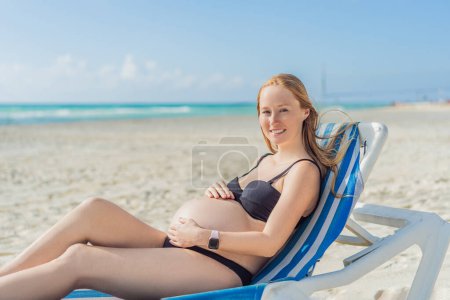 Téléchargez les photos : Se prélasser dans la tranquillité balnéaire, une femme enceinte se prélasse sur une chaise longue, embrassant l'ambiance apaisante de la plage pour un moment de détente sereine. - en image libre de droit