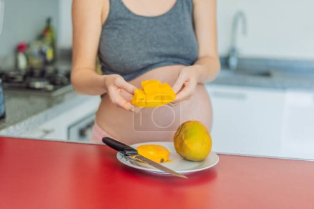 Foto de Una mujer embarazada hábil corta delicadamente en un mango maduro, saboreando un momento de alegría culinaria y nutriendo su embarazo con una golosina fresca y sabrosa. - Imagen libre de derechos