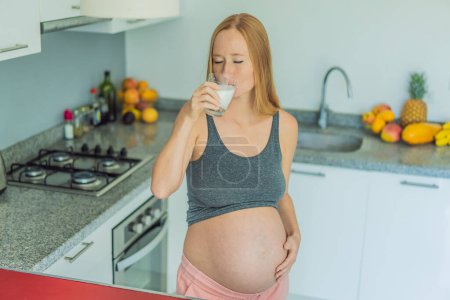 Beim Abwägen der Vor- und Nachteile von Milch während der Schwangerschaft steht eine nachdenkliche Schwangere mit einem Glas in der Küche und überlegt, ob sie und ihre Babys Milch gut aufnehmen oder vermeiden sollen.