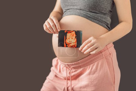 Werdende Mutter verbindet sich zärtlich mit ihrem ungeborenen Kind und hält Ultraschallbild an ihren Schwangerschaftsbauch.