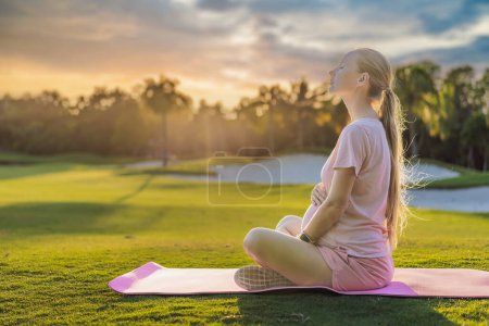 Energetic pregnant woman takes her workout outdoors, using an exercise mat for a refreshing and health-conscious outdoor exercise session.