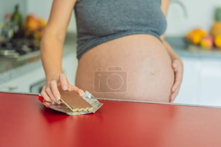 Téléchargez les photos : Contemplant le doux dilemme, une femme enceinte réfléchit à la décision de se livrer au chocolat pendant la grossesse, pesant l'impact potentiel des friandises délicieuses sur son voyage maternel. - en image libre de droit