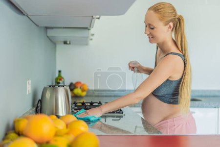 Efficient and dedicated, a pregnant woman tackles kitchen chores, ensuring a clean and organized space, exemplifying resilience and care during her pregnancy.