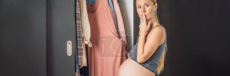 BANNER, LANG FORMAT Eine Schwangere hat nichts zu tragen. Eine schwangere Frau steht vor einem Kleiderschrank und weiß nicht, was sie anziehen soll, weil die Kleidung nicht auf sie passt.