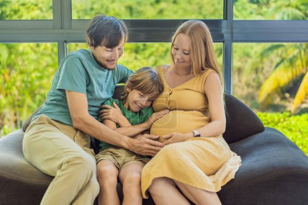 Gemütliche Familienzeit zu Hause, während schwangere Mutter, Vater und Sohn gemeinsame Momente auf dem Sofa genießen, herzerwärmende Erinnerungen wecken und die gemeinsame Zeit wertschätzen.
