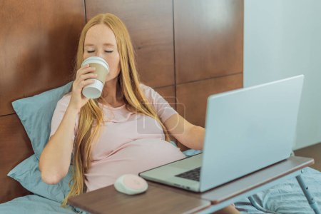 Findige Schwangere arbeitet von der gemütlichen Enge ihres Bettes zu Hause aus und verbindet Produktivität mit einer beruhigenden Kaffeepause während der Fernbedienung.