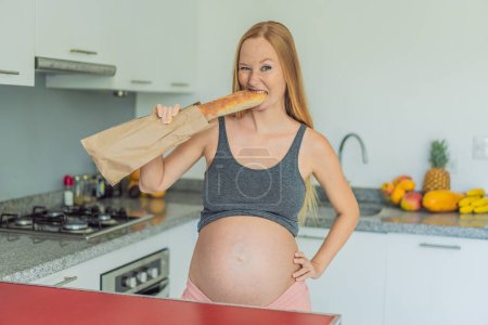 Femme enceinte mangeant du pain dans la cuisine. Explorer l'impact du gluten pendant la grossesse : comprendre les avantages et les risques potentiels pour la santé maternelle et le développement du f?tus.