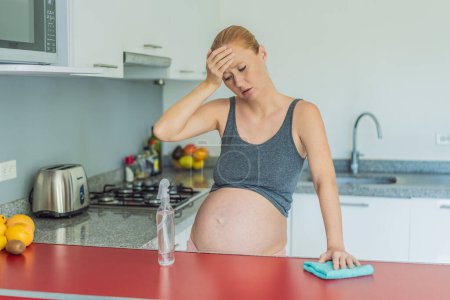 Eine müde Schwangere sitzt nach dem Putzen in der Küche. Gesundheit und Vitalität einer Schwangeren.