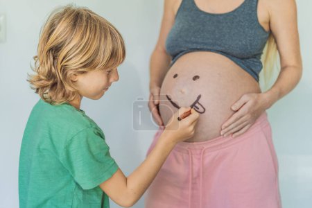 Momento adorable como un hijo añade un toque de alegría a su embarazo madres, dibujando juguetonamente una cara divertida en su protuberancia bebé, creando recuerdos preciados.