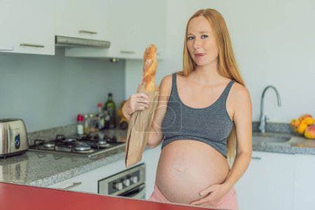 Pregnant woman eating bread in the kitchen. Exploring the impact of gluten during pregnancy: understanding the potential benefits and risks for maternal health and fetal development.