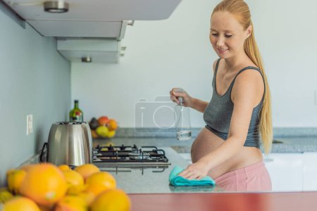 Effizient und engagiert geht eine schwangere Frau die Küchenarbeit an, sorgt für einen sauberen und geordneten Raum und ist ein Beispiel für Widerstandsfähigkeit und Pflege während ihrer Schwangerschaft.