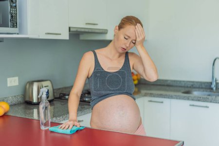 Eine müde Schwangere sitzt nach dem Putzen in der Küche. Gesundheit und Vitalität einer Schwangeren.
