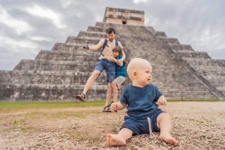Father and two sons tourists observing the old pyramid and temple of the castle of the Mayan architecture known as Chichen Itza. These are the ruins of this ancient pre-columbian civilization and part