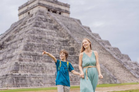 Hermosa turista y su bebé observando la antigua pirámide y templo del castillo de la arquitectura maya conocido como Chichén Itzá. Estas son las ruinas de esta antigua civilización precolombina