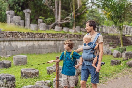 Foto de Padre y dos hijos turistas observando la antigua pirámide y templo del castillo de la arquitectura maya conocido como Chichén Itzá. Estas son las ruinas de esta antigua civilización precolombina y parte - Imagen libre de derechos
