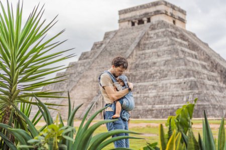Foto de Padre e hijo turistas observando la antigua pirámide y templo del castillo de la arquitectura maya conocido como Chichén Itzá. Estas son las ruinas de esta antigua civilización precolombina y parte de - Imagen libre de derechos