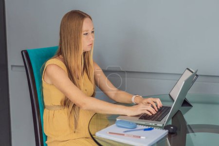 Beautiful pregnant woman working on laptop. Young businesswoman working in her office.