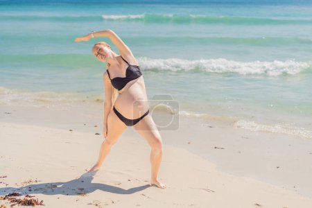 Harmonizing mind and body, a pregnant woman gracefully practices yoga on the beach, embracing the serenity of the seaside for a tranquil and mindful pregnancy experience.