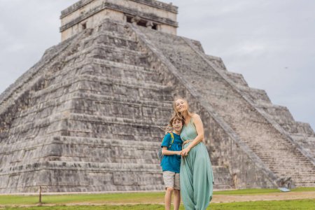 Hermosa turista y su bebé observando la antigua pirámide y templo del castillo de la arquitectura maya conocido como Chichén Itzá. Estas son las ruinas de esta antigua civilización precolombina