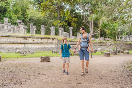 Father and two sons tourists observing the old pyramid and temple of the castle of the Mayan architecture known as Chichen Itza. These are the ruins of this ancient pre-columbian civilization and part