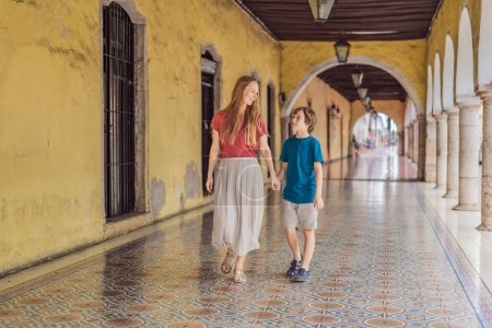 Photo for Mother and son tourists explore the vibrant streets of Valladolid, Mexico, immersing herself in the rich culture and colorful architecture of this charming colonial town. - Royalty Free Image