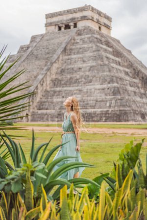 Beautiful tourist woman observing the old pyramid and temple of the castle of the Mayan architecture known as Chichen Itza. These are the ruins of this ancient pre-columbian civilization and part of