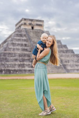 Foto de Hermosa turista y su hijo bebé observando la antigua pirámide y templo del castillo de la arquitectura maya conocido como Chichén Itzá. Estas son las ruinas de este antiguo precolombino - Imagen libre de derechos