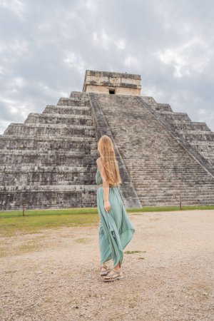 Foto de Hermosa turista observando la antigua pirámide y templo del castillo de la arquitectura maya conocido como Chichén Itzá. Estas son las ruinas de esta antigua civilización precolombina y parte de - Imagen libre de derechos