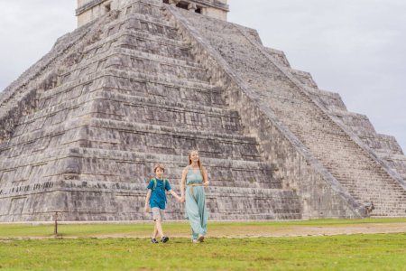 Beautiful tourist woman and her baby observing the old pyramid and temple of the castle of the Mayan architecture known as Chichen Itza. These are the ruins of this ancient pre-columbian civilization