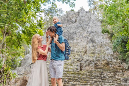 Mom, dad and baby tourists at Coba, Mexico. Ancient mayan city in Mexico. Coba is an archaeological area and a famous landmark of Yucatan Peninsula. Cloudy sky over a pyramid in Mexico.