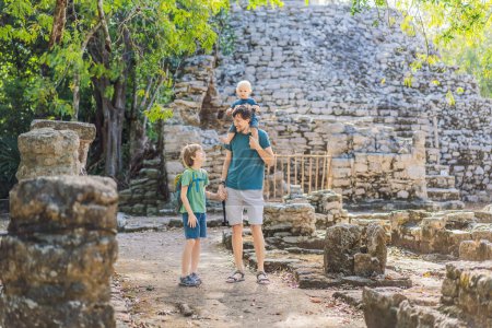 Papá con dos hijos turistas en Coba, México. Antigua ciudad maya en México. Coba es un área arqueológica y un famoso hito de la península de Yucatán. Cielo nublado sobre una pirámide en México.