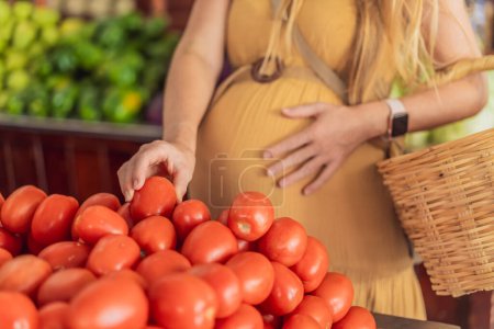 In a grocery store, a pregnant woman stands by a fruit stand, surrounded by various natural foods. She is in a public space where the local market offers whole foods for trade Pregnant woman buying