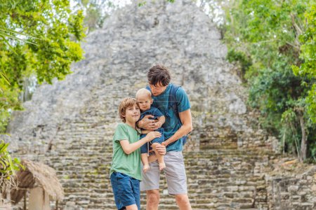 Papá con dos hijos turistas en Coba, México. Antigua ciudad maya en México. Coba es un área arqueológica y un famoso hito de la península de Yucatán. Cielo nublado sobre una pirámide en México.