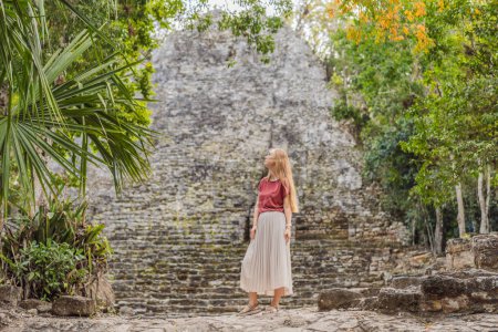 Woman tourist at Coba, Mexico. Ancient mayan city in Mexico. Coba is an archaeological area and a famous landmark of Yucatan Peninsula. Cloudy sky over a pyramid in Mexico.