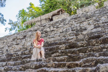 Woman tourist at Coba, Mexico. Ancient mayan city in Mexico. Coba is an archaeological area and a famous landmark of Yucatan Peninsula. Cloudy sky over a pyramid in Mexico.