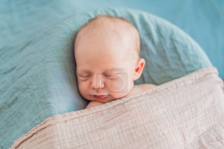 Le bébé dort paisiblement dans son nid confortable. Séance photo nouveau-né capture l'innocence sereine et la chaleur des premiers moments.