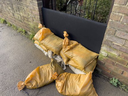 Photo for Sandbags and flood gate on protecting property from floodwater in Tewkesbury, England after the River Severn burst its banks. Sandbags and temporary flood gates stop flood water entering houses. - Royalty Free Image