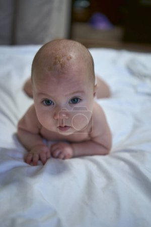 Téléchargez les photos : Bébé de quatre mois couché sur le lit - en image libre de droit