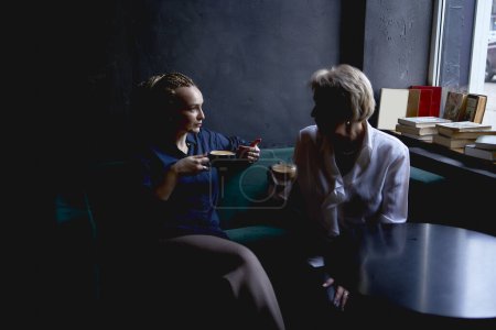 Foto de Anciana madre e hija de mediana edad bebiendo café y hablando en un café - Imagen libre de derechos